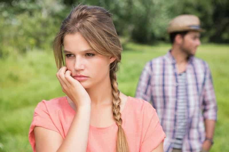 worried stressed woman with man in background